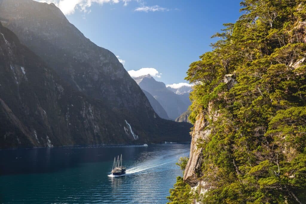 Boat cruising along the calm waters of Milford Sound surrounded by towering mountains