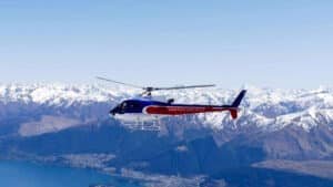 Helicopter flying above Milford Sound with towering mountains and deep fjords below