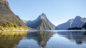 Crystal-clear Mirror Lake reflecting surrounding mountains and trees in Milford Sound