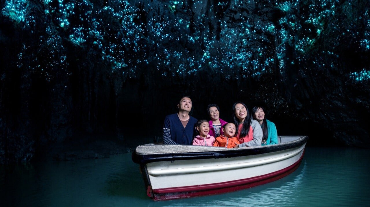 Small boat floating inside Waitomo Glowworm Caves with glowworms illuminating the cave ceiling