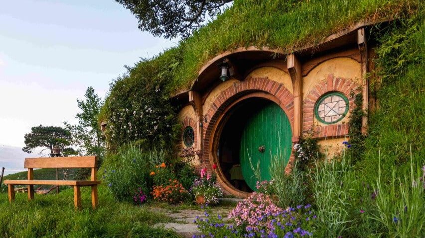 Detailed close-up of a Hobbiton hobbit hole home with round door and lush garden surroundings