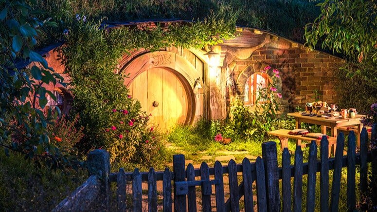 Hobbiton village illuminated at night with glowing lights in round-door homes