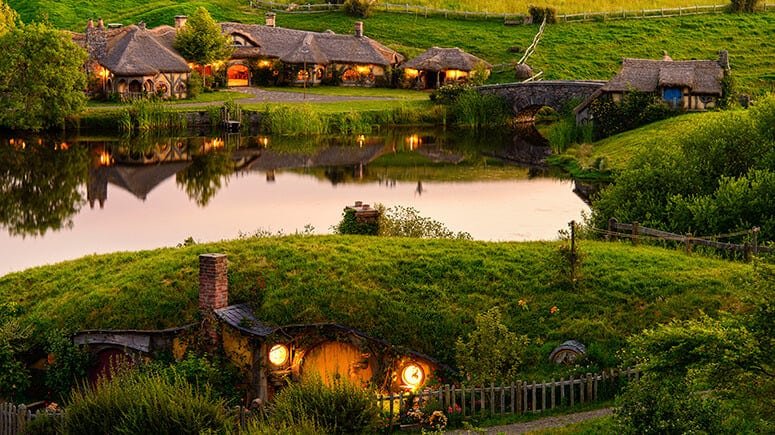 Picturesque view of Hobbiton village with charming hobbit holes nestled in lush green hills