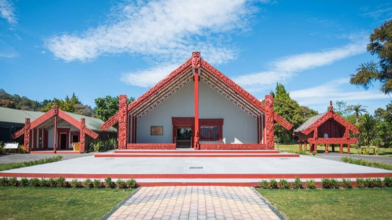 Exterior view of a traditional Māori marae building at Te Puia with carved wooden panels and meeting house