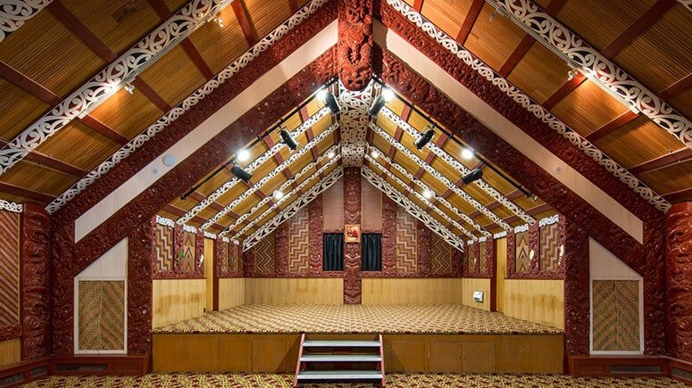 Traditional Māori marae interior with intricate carvings and woven panels at Te Puia