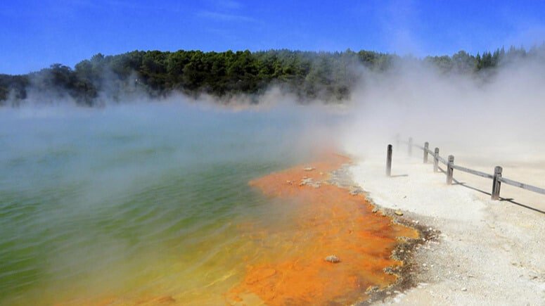 Scenic geothermal lake with steam rising from geysers and hot springs in Rotorua