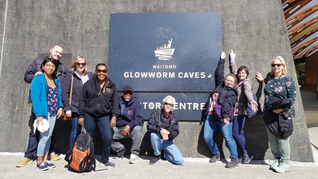 Visitors gathered around educational glowworm signage at the Waitomo Glowworm Caves tour centre