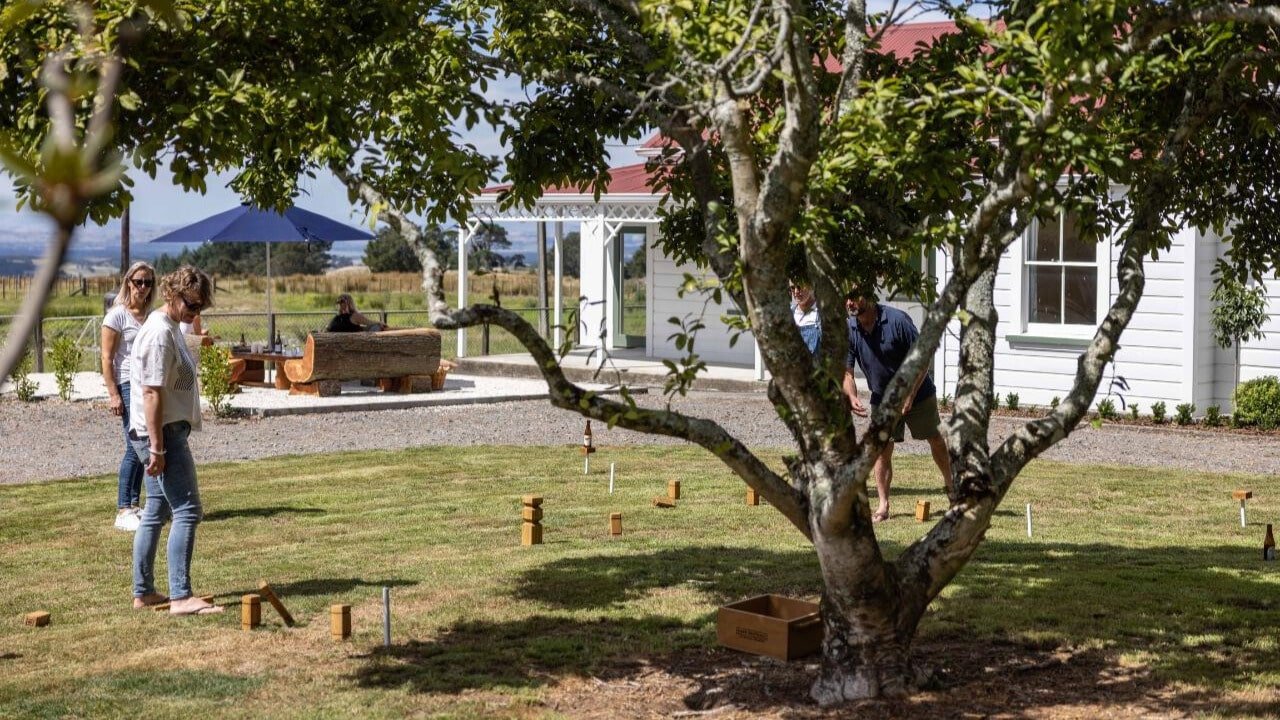 Guests playing kubbs lawn game with drinks and nibbles nearby