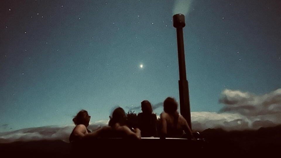Guests relaxing in a wood-fired hot tub under the stars at Blackburn Ridge Rural Retreat