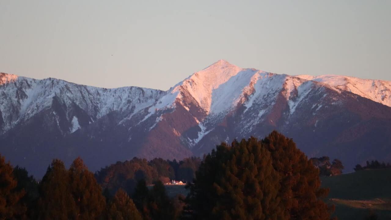 Snow-covered mountain ranges towering above rural landscapes