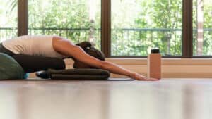 Person practicing restorative yoga poses in a peaceful retreat setting