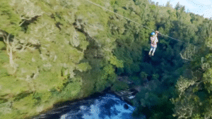 Adventurer ziplining high above a river at Okere Falls in Rotorua