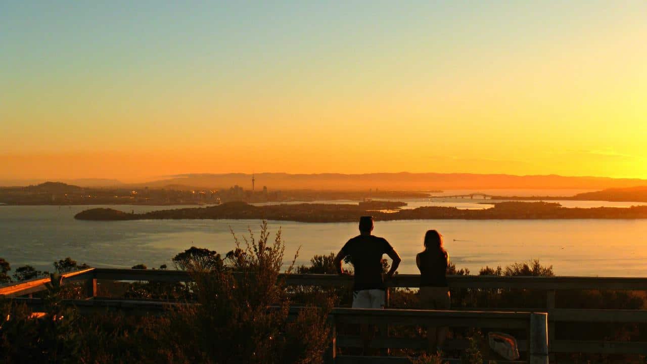 Sunset over Rangitoto Island with Auckland City skyline and Sky Tower in the background
