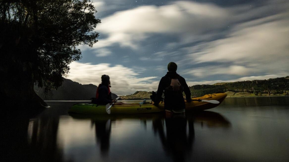 Kayaking on calm water under a starry evening sky during Rotorua glow worm tour