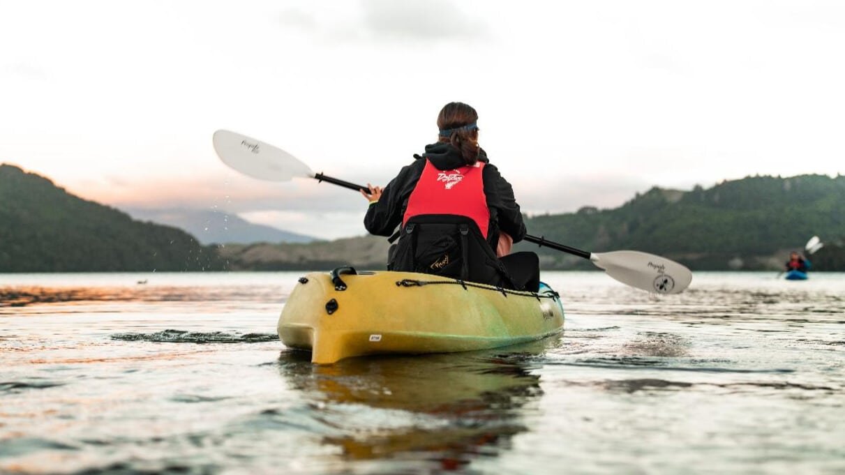 Kayak gliding on smooth waters during a glowing sunset in Rotorua