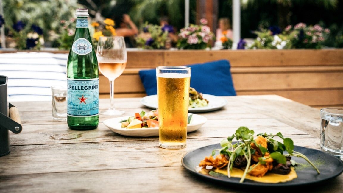 Chilled beer and wine glasses sweating on the table beside a delicious food spread on Waiheke Island