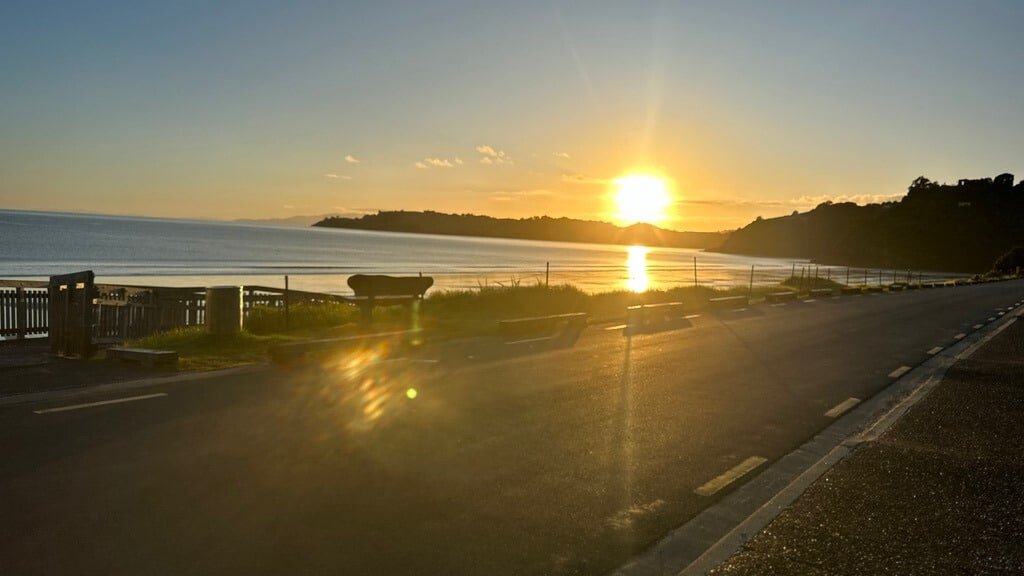 Sunset casting warm orange glow behind the edge of Waiheke Island