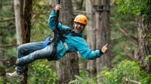 Person giving thumbs up while ziplining through native bush in Coromandel
