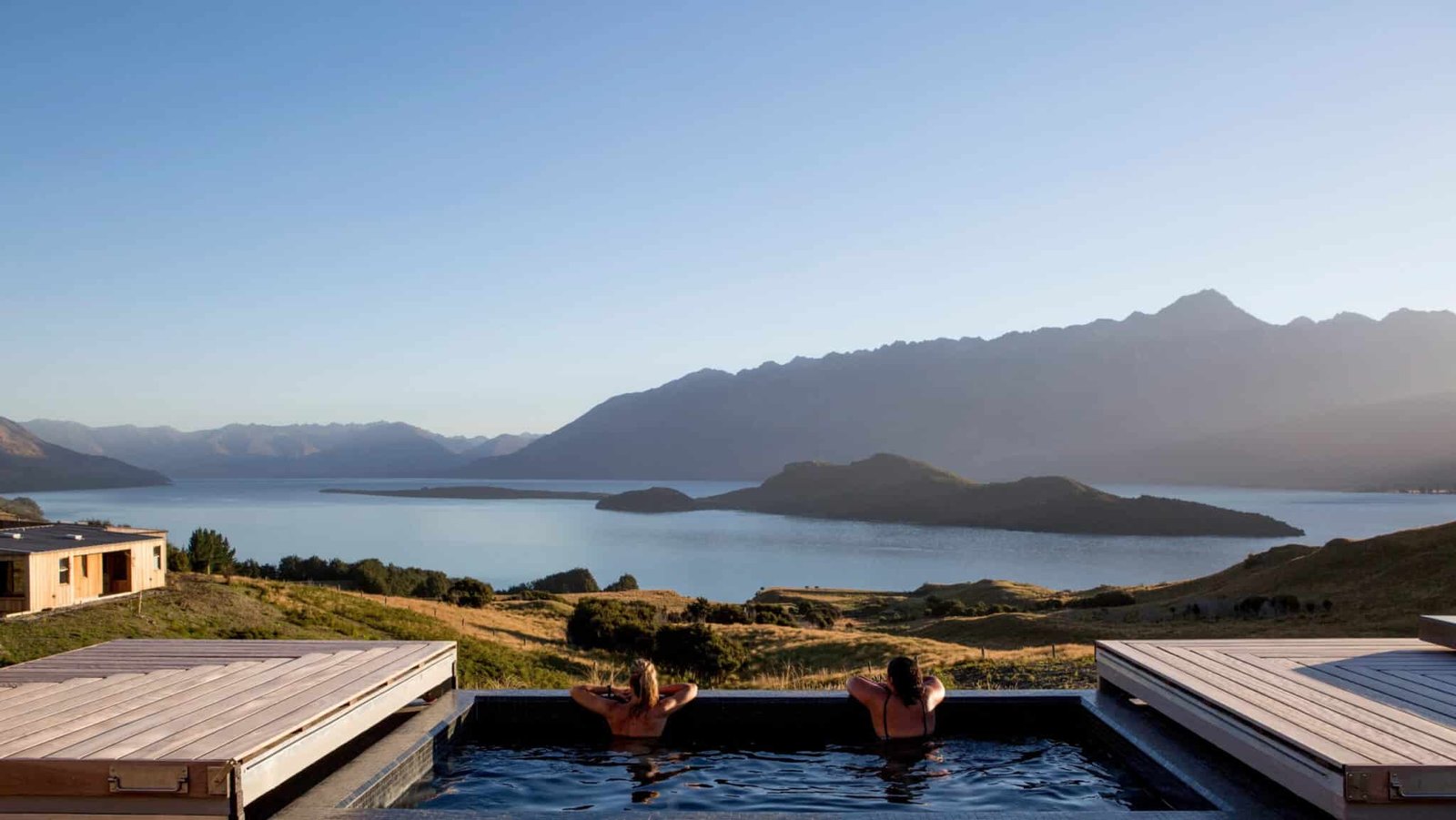 View from the spa pool overlooking a tranquil lake surrounded by majestic mountains at Aroha Wellness Retreat.