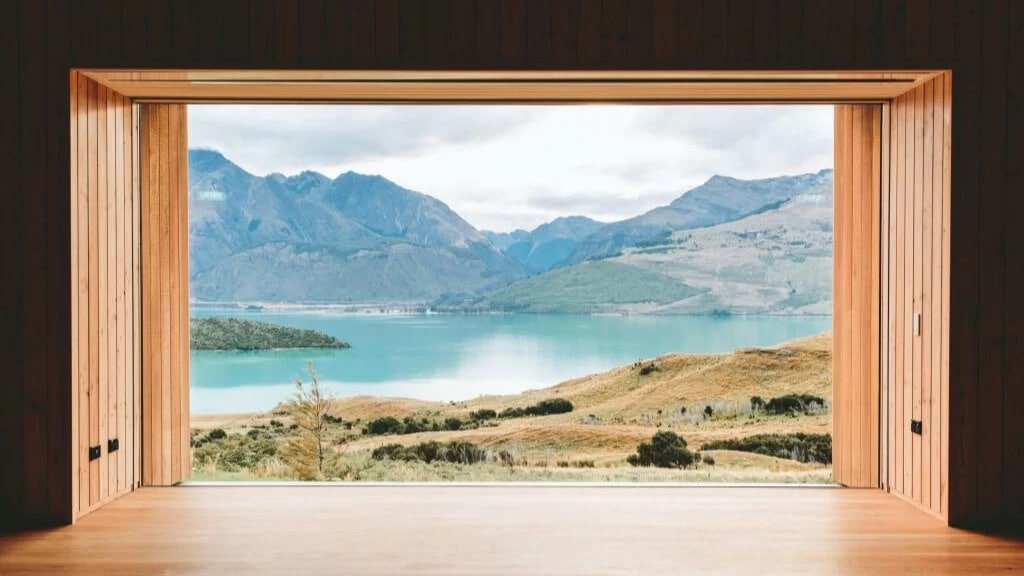 Framed peaceful view from yoga studio overlooking rolling hills, lakes, and mountains at Aroha Wellness Retreat.