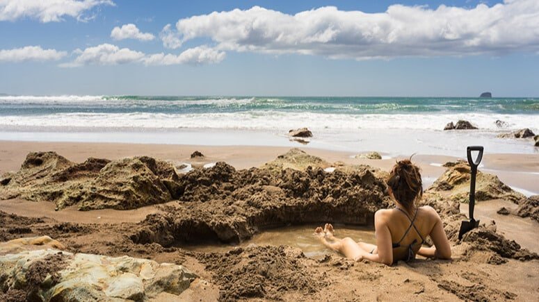 Person soaking in a natural hot water pool on Hot Water Beach, Coromandel