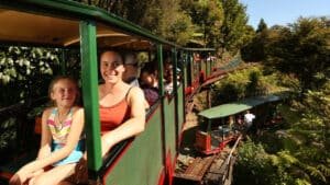 Families riding the Driving Creek Railway train over a scenic bridge in Coromandel, New Zealand