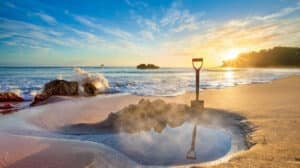 Sunset casting warm golden light over Hot Water Beach’s sandy shores and rock formations