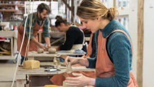 Hands shaping clay and adding detail to a pottery piece during a class at Driving Creek.