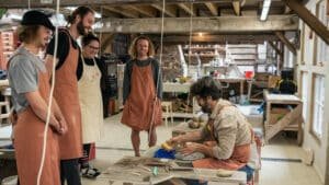 Small group of participants attentively learning pottery techniques from an instructor at Driving Creek.
