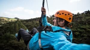 Person ziplining above lush native bush with expansive scenic views in Coromandel