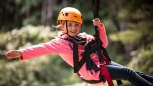 Family enjoying ziplining adventure through lush native forest in Coromandel