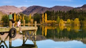 Person sitting on a wooden jetty overlooking Lake Dunstan at Cromwell Heritage Precinct
