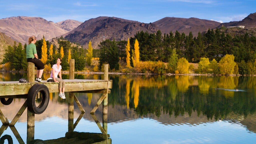 Person sitting on a wooden jetty overlooking Lake Dunstan at Cromwell Heritage Precinct