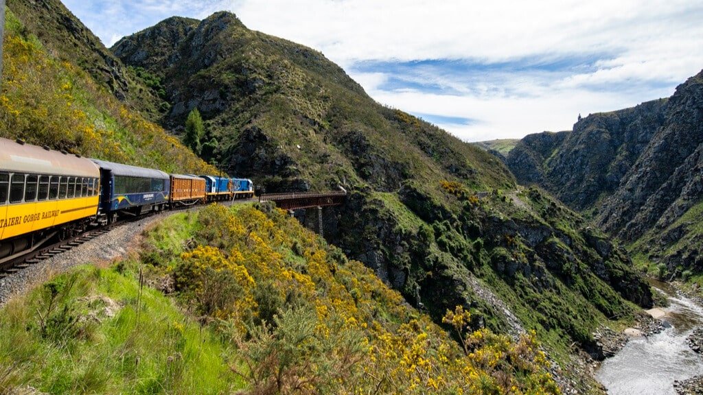 Taieri Gorge Railway train crossing a high bridge above a valley and winding river with scenic views
