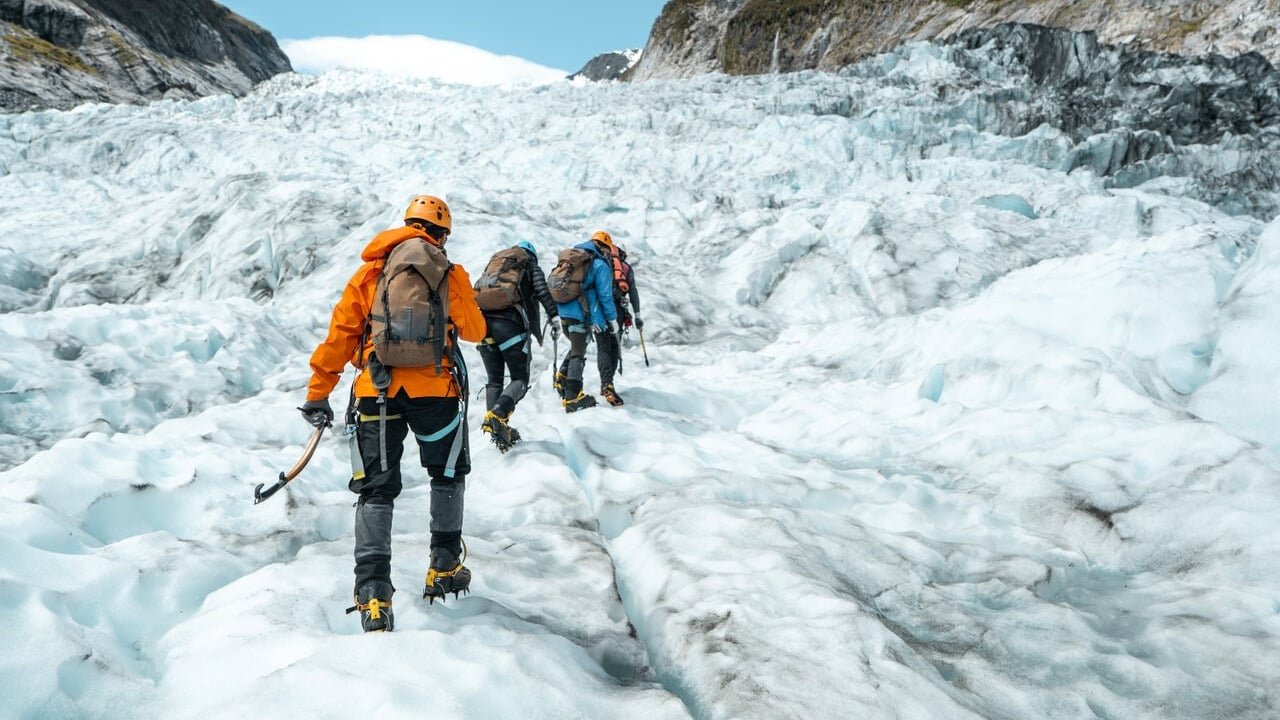 Adventurers ice tramping on Fox Glacier during a guided mountaineering tour.