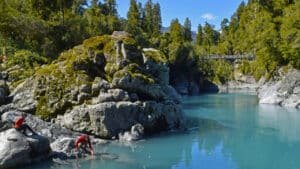 Rope suspension bridges crossing over blue river waters with rock pools in Hokitika Gorge, New Zealand.