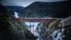 TranzAlpine train crossing the massive staircase viaduct high in the mountains over a river in New Zealand.