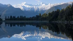 Snow-capped mountains perfectly reflected in the calm waters of Lake Matheson on New Zealand’s West Coast.