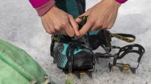 Tramper fitting ice spikes on boots before a guided helihike tour of Tasman Glacier near Queenstown