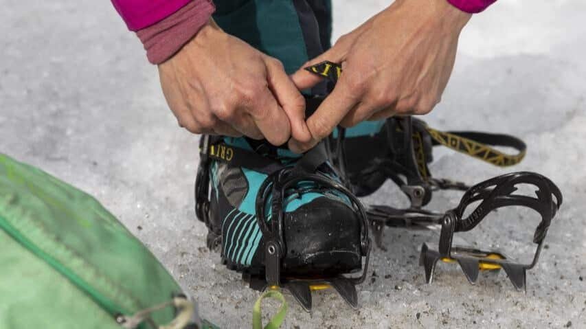Tramper fitting ice spikes on boots before a guided helihike tour of Tasman Glacier near Queenstown