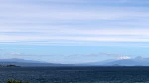 Snow-capped mountain in the distance across a calm New Zealand lake or bay