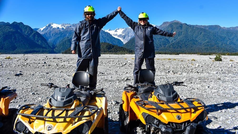 Group of people posing and smiling on quad bikes during an off-road adventure tour in Franz Josef.