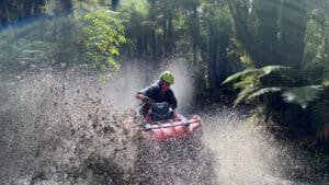 4x4 buggy splashing through muddy water on a rugged off-road trail in Franz Josef.