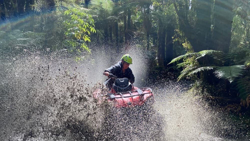 4x4 buggy splashing through muddy water on a rugged off-road trail in Franz Josef.