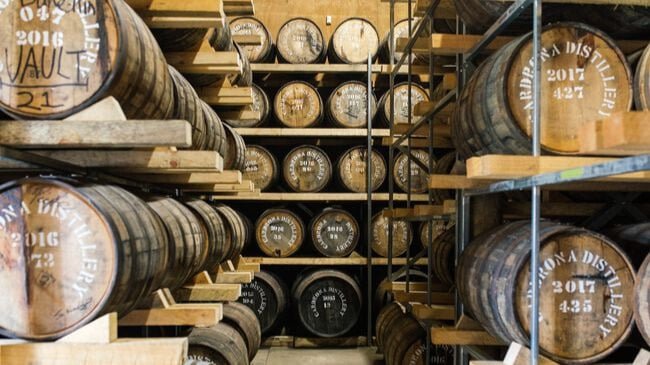 Stacked wooden barrels in the cellar of Cardrona distillery during the Queenstown Gin Tour.
