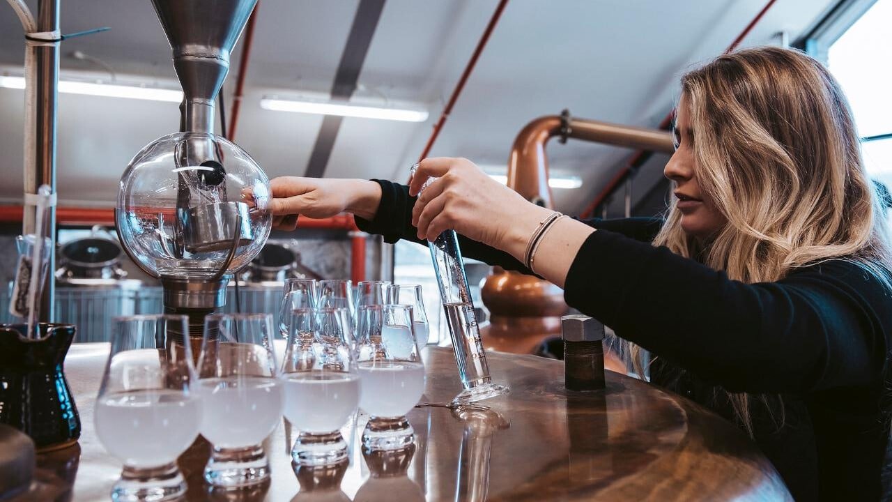 Measuring test tube and cup alongside a line of craft gin bottles during the distilling process on the Queenstown Gin Tour.