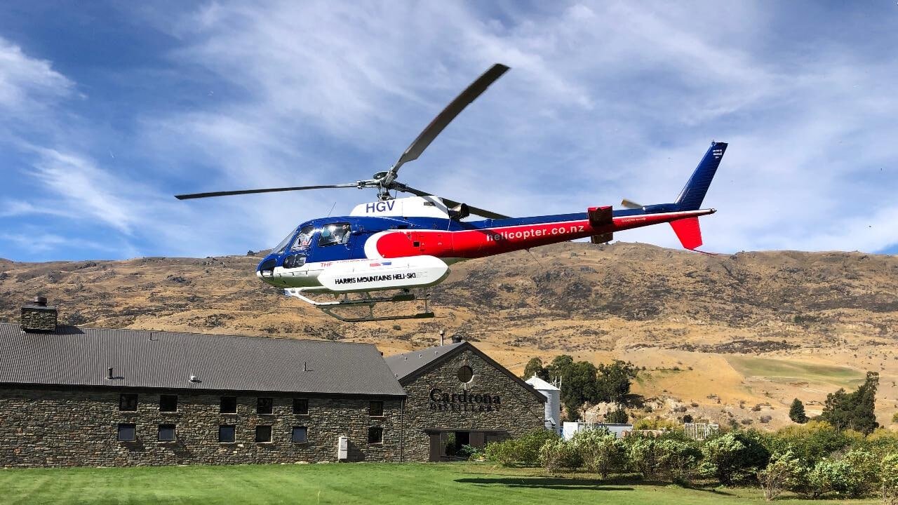 Helicopter landing at Cardrona Distillery during Queenstown heli-gin tour with mountain backdrop