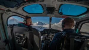 Helicopter cockpit view looking out over snow-covered mountains during Queenstown heli-wine tour