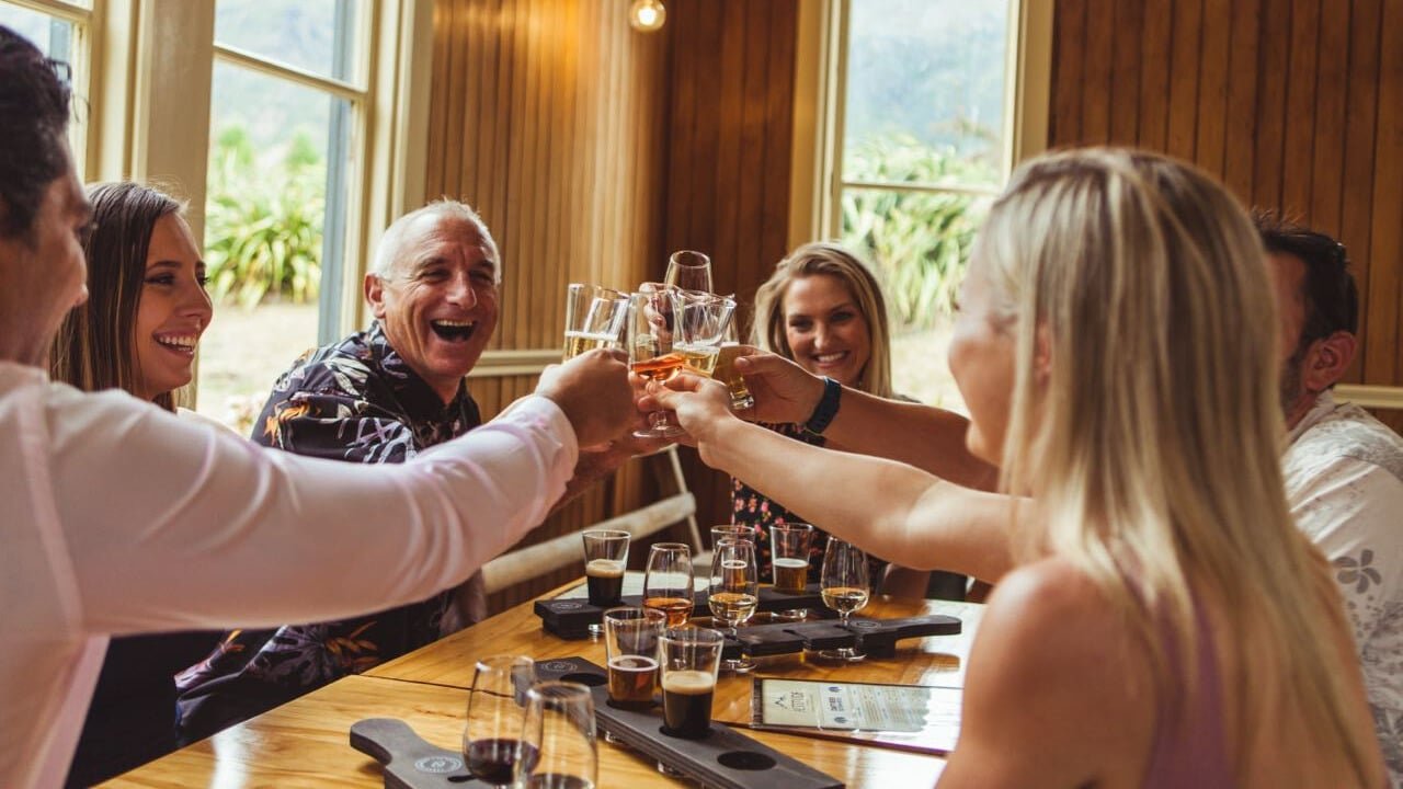 Group of friends raising glasses and cheering during a Queenstown twilight wine and craft beer tour