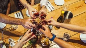 A group raising wine glasses in a toast over a lunch table at Kinross Winery during the Queenstown Wine Sampler Tour.